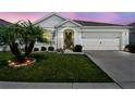 Charming single-story home with well-maintained lawn, landscaping, and an attached two-car garage at dusk at 879 Killarney Ln, Auburndale, FL 33823