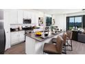 Modern kitchen with white cabinets, stainless steel appliances, a central island, and barstool seating at 258 Puma Loop, Groveland, FL 34736