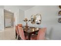 Elegant dining area with a dark wood table, pink chairs, and decorative mirrors on the wall at 466 Puma Loop, Groveland, FL 34736