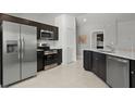 Modern kitchen with stainless steel appliances, dark wood cabinetry, and bright countertops at 466 Puma Loop, Groveland, FL 34736