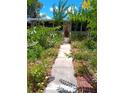 Inviting walkway leading to a charming home exterior with lush landscaping and blooming flowers at 109 Fern Dr, Debary, FL 32713