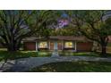 Charming brick home with mature trees, well-manicured lawn, and inviting curb appeal at twilight at 1203 Lake Miriam Dr, Lakeland, FL 33813