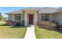 Close up of a beautiful front entry, showcasing a pathway, plants and a stylish door at 13581 Sw 48Th Ct, Ocala, FL 34473