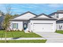 Attractive single-story home featuring manicured lawn, blue front door, and two-car garage at 13279 Tula Loop, Astatula, FL 34705