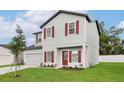 Charming two-story home featuring red window shutters, a gray exterior, and a well-maintained front lawn at 13450 Leaping Water Way, Astatula, FL 34705
