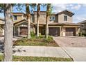 Well-manicured townhome featuring a two-car garage, paver driveway, and lush landscaping at 8983 Azalea Sands Ln # 8983, Davenport, FL 33896