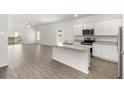 Bright, modern kitchen featuring stainless steel appliances, a functional island, and sleek, light-toned wood flooring at 1782 White Elephant Loop, Winter Haven, FL 33884