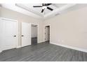 Main bedroom featuring wood-look floors, neutral walls, tray ceiling with ceiling fan and two closets at 7701 Somersworth Dr, Kissimmee, FL 34747