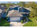 Aerial view of a two-story blue home with an attached garage and lush green lawn at 14610 Astina Way, Orlando, FL 32837