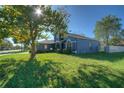 The side view of this two-story home shows the blue siding, lush yard, and bright sun at 14610 Astina Way, Orlando, FL 32837