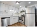 Modern kitchen featuring stainless steel appliances, sleek white cabinets, and durable hardwood floors at 4215 S Semoran Blvd # 3, Orlando, FL 32822