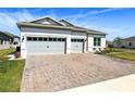Charming home with a well-manicured lawn, a stone driveway, and a three car garage at 3158 Sailing Pier Ave, Winter Garden, FL 34787