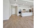 Open-concept living room and kitchen with stainless appliances and light wood-look tile flooring at 3158 Sailing Pier Ave, Winter Garden, FL 34787