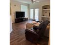 Cozy living room with ceiling fan, wood floors, built in shelves, and sliding glass doors at 3301 Soho St # 102, Orlando, FL 32835
