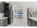 Spacious kitchen with black cabinets, white countertops, stainless steel appliances, and a view to the game room at 1568 Maidstone Ct, Davenport, FL 33896