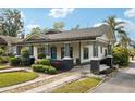 Quaint home featuring a covered porch, manicured landscaping, and a patterned driveway at 515 Frank Lloyd Wright Way, Lakeland, FL 33803