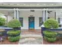 Inviting front porch with meticulously trimmed shrubs and a charming blue door at 515 Frank Lloyd Wright Way, Lakeland, FL 33803
