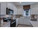 Well-lit kitchen with stainless steel appliances, white cabinetry, a window and tiled backsplash at 8207 Sw 52Nd Lane Rd, Ocala, FL 34481