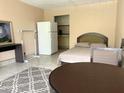 Studio bedroom featuring a comfortable bed and small kitchen area with a refrigerator at 7900 S Orange Blossom Trl # 1099, Orlando, FL 32809