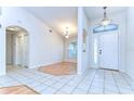 Bright entryway featuring neutral tile flooring, arched doorway, chandelier, and a window above the front door at 3518 Remington Oaks Way, Lakeland, FL 33810