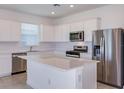 Modern kitchen featuring stainless steel appliances, a center island, and white cabinets at 8953 Wildlight Trl, Wildwood, FL 34785