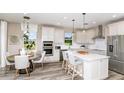 Bright, open kitchen with white cabinets, stainless steel appliances, island with seating, adjacent dining area at 8953 Wildlight Trl, Wildwood, FL 34785