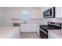 Bright kitchen boasts white cabinets, stainless steel appliances, and quartz countertops at 8953 Wildlight Trl, Wildwood, FL 34785