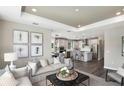 Open-concept living room with modern furnishings, gray sofa and decor, connected to kitchen at 8953 Wildlight Trl, Wildwood, FL 34785