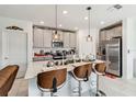 Modern kitchen featuring white cabinets, stainless steel appliances, and a spacious island with barstool seating at 356 Loch Ct, Davenport, FL 33837