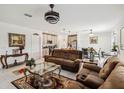 Open-concept living room with a brown sofa, a glass coffee table, and views of the dining and kitchen areas at 356 Loch Ct, Davenport, FL 33837