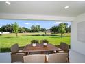 Covered patio with dining table, offering serene views of the pond and lush backyard at 1022 Brimstone Cir, Winter Haven, FL 33884