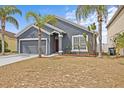 Inviting single-story home with a gray exterior, lush landscaping and a two-car garage at 438 Cotswold Cir, Davenport, FL 33837