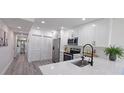 Modern white kitchen with stainless steel appliances, an island sink, and gray wood flooring at 25322 Columbia Cir, Lake Wales, FL 33898