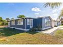 View of the blue home showcasing the bright windows and landscaped yard at 702 Turnberry Ln, Lady Lake, FL 32159