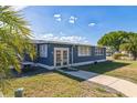 Angle view of the blue home with front patio access and well-kept landscape at 702 Turnberry Ln, Lady Lake, FL 32159