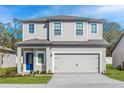 Charming two-story home featuring a well-manicured lawn, gray siding, and a vibrant blue front door at 13280 Tula Loop, Astatula, FL 34705