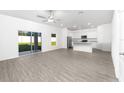 Bright open-plan living space with wood-style flooring, white walls, ceiling fan, and sliding glass doors at 13280 Tula Loop, Astatula, FL 34705