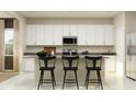 A modern kitchen with white cabinetry and black barstools at the breakfast bar at 698 Peroni Ave, Debary, FL 32713
