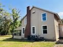 Exterior view of the two-story home featuring a brick chimney, white framed windows, and a screened porch at 18700 Ravenswood Rd, Altoona, FL 32702
