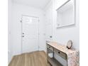 Bright entryway featuring wood floors, a white front door, and a stylish console table with decorative accents at 670 Campo Ln, Davenport, FL 33837