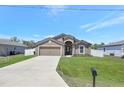Charming single-story home with a well-manicured lawn, concrete driveway, and an attached two-car garage at 329 W Aster Ct, Poinciana, FL 34759