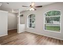 Bright living room with light wood-look flooring, a ceiling fan, and large windows at 541 Willet Cir, Auburndale, FL 33823