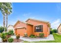 Side view of an orange stucco single-story home with well-maintained landscaping and blue skies at 505 Millifiora Ln, Kissimmee, FL 34759