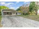 Spacious driveway leading to a carport alongside a cozy single-story home under a partly cloudy sky at 803 Mccranie Rd, Lakeland, FL 33809