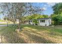 Single-story home with black shutters surrounded by a lush lawn and decorated with colorful flowers at 803 Mccranie Rd, Lakeland, FL 33809