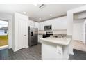 Modern kitchen featuring white cabinets, stainless steel appliances, granite countertops, and durable gray wood-look flooring at 3824 Corsican Pl, Lake Alfred, FL 33850