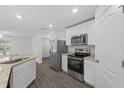 Modern kitchen features stainless steel appliances, granite countertops, white cabinets, and wood-look floors at 481 Danube Dr, Poinciana, FL 34759