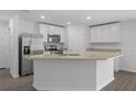 Bright kitchen boasts granite countertops, stainless steel appliances, white cabinets, and wood-look floors at 481 Danube Dr, Poinciana, FL 34759