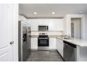 Modern kitchen featuring stainless steel appliances, granite countertops, and sleek gray wood flooring at 3829 Corsican Pl, Lake Alfred, FL 33850