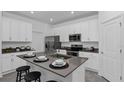 Bright kitchen featuring white cabinets, stainless steel appliances, an island, and stool seating at 611 Terrapin Dr, Debary, FL 32713